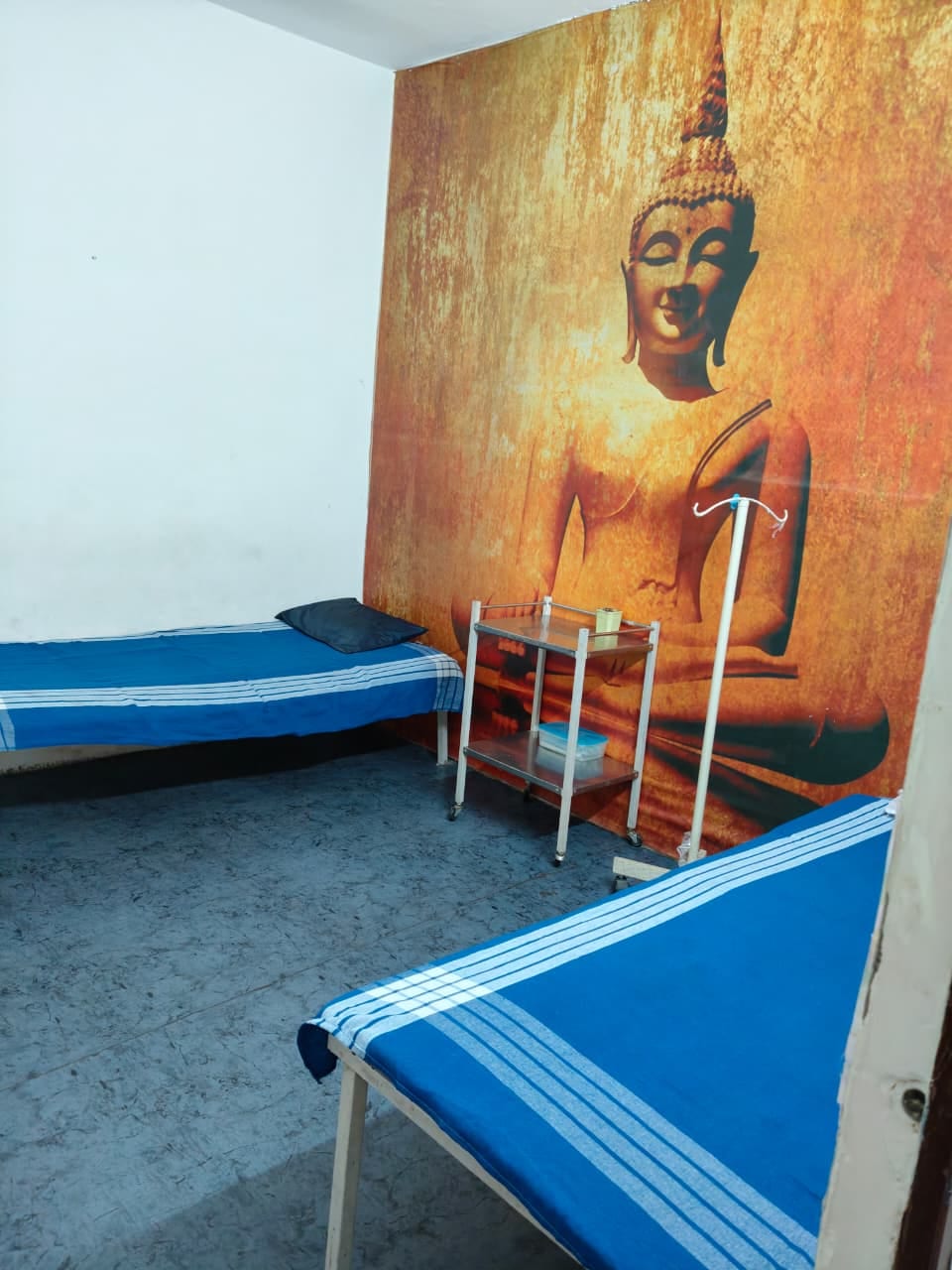 Two patient beds and a Buddha mural in the rest room at Uchit Diagnostic